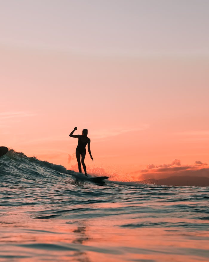pexels-photo-4322441 Silhouette of a surfer enjoying the waves at sunset, evoking adventure and leisure.